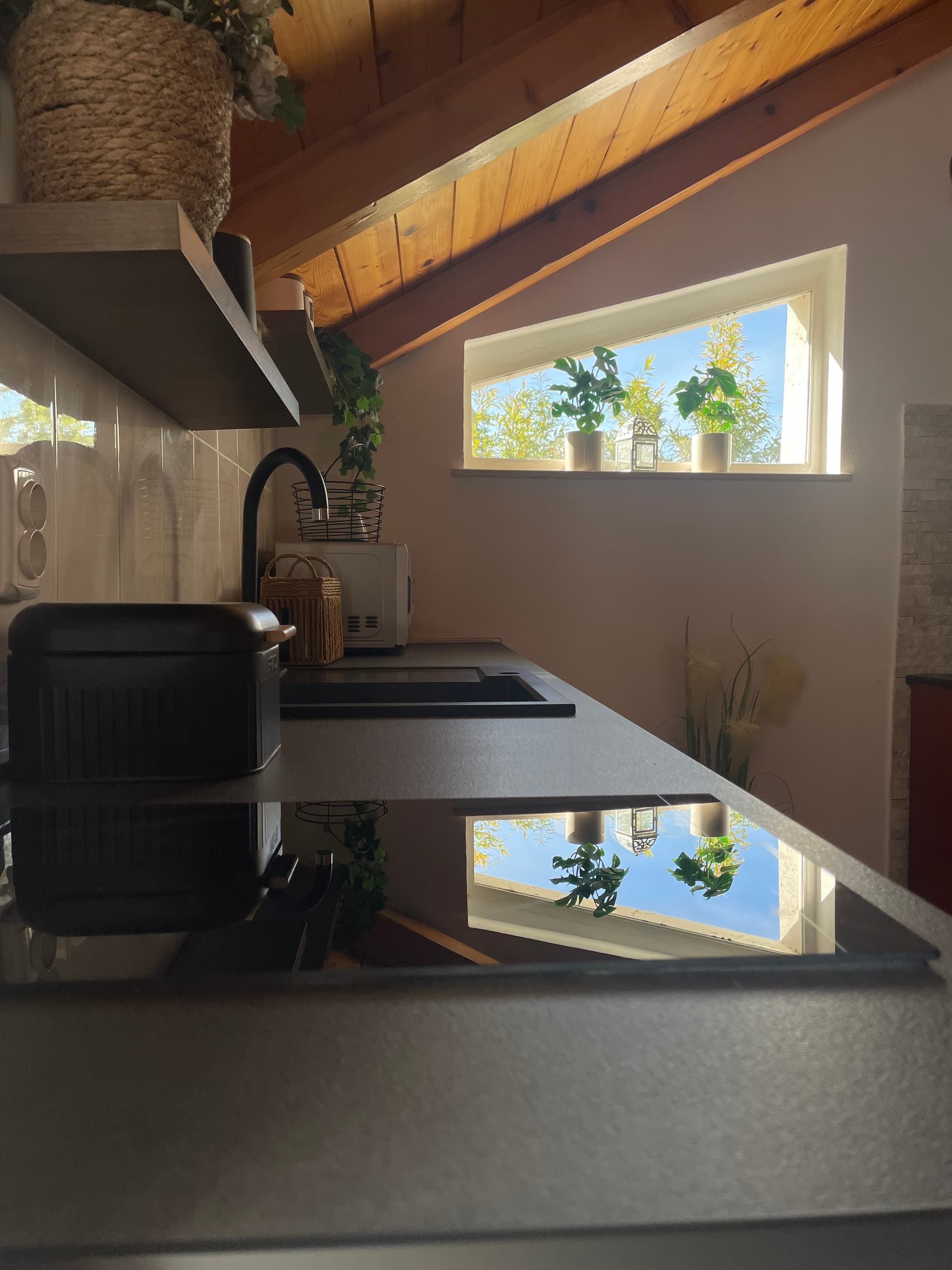 Interijer manjeg apartmana pod drvenim skošenim stropom s dva krovna prozora i puno prirodnog svjetla