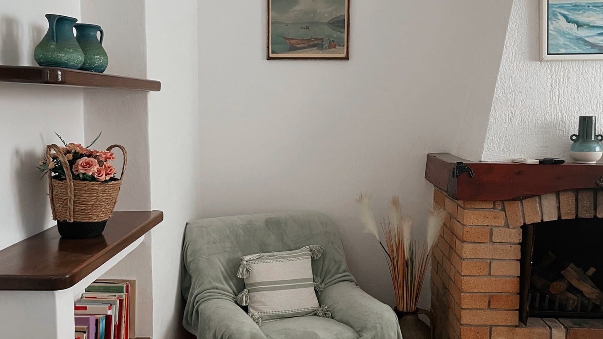Autentičan kutak apartmana za iznajmljivanje s foteljom, zidanim kaminom, starim slikama i keramičkim detaljima