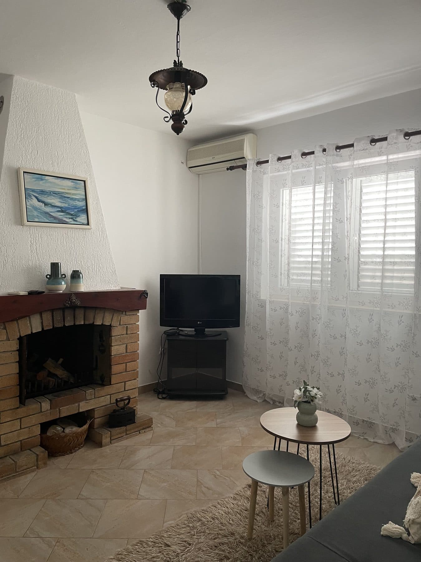 Svijetli dnevni boravak apartmana sa zidanim kaminom, televizorom, klimom i velikim prozorom